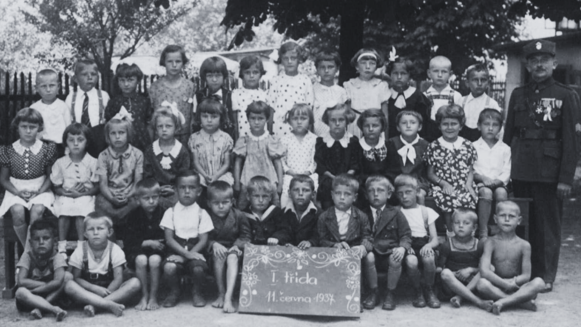 Řídící učitel smíšené obecné školy v Michálkovicích F. V. Hrbáč se žactvem první třídy na snímku pořízeném dne 11. června 1937, nedlouho před oslavami 20. výročí zborovské bitvy.